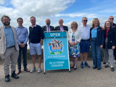 In a floral blue and white summery frock, Anna Firth MP stands with her fellow Southend MP Sir James Duddridge and a number of other men on Southend's seafront